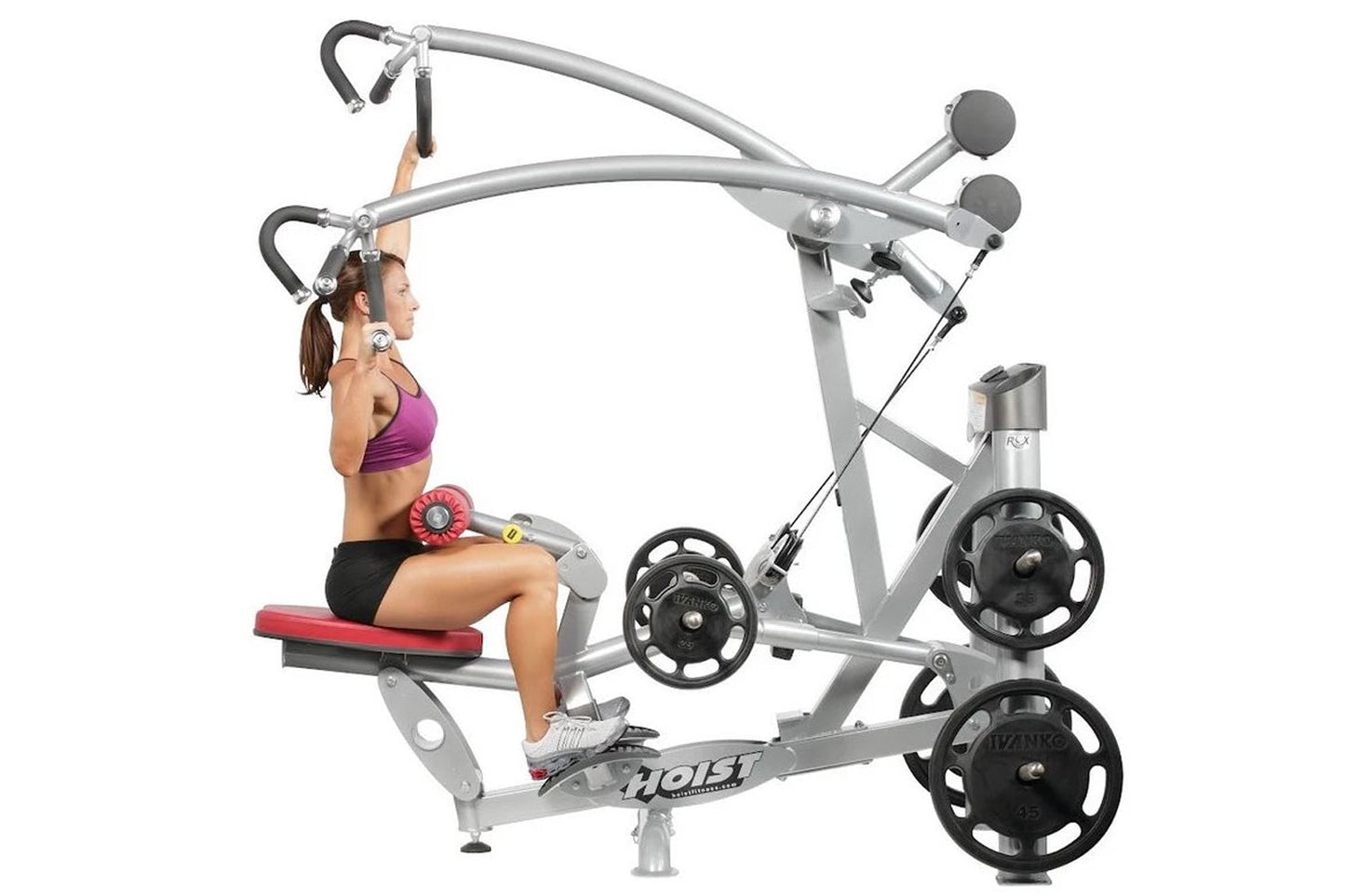 Silver and black lat pulldown machine with weight plates, woman in purple top demonstrating seated exercise on red seat with 