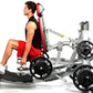 Man using silver and red Hoist ROC-IT leg press machine with black weight plates, wearing red shorts and black tank top