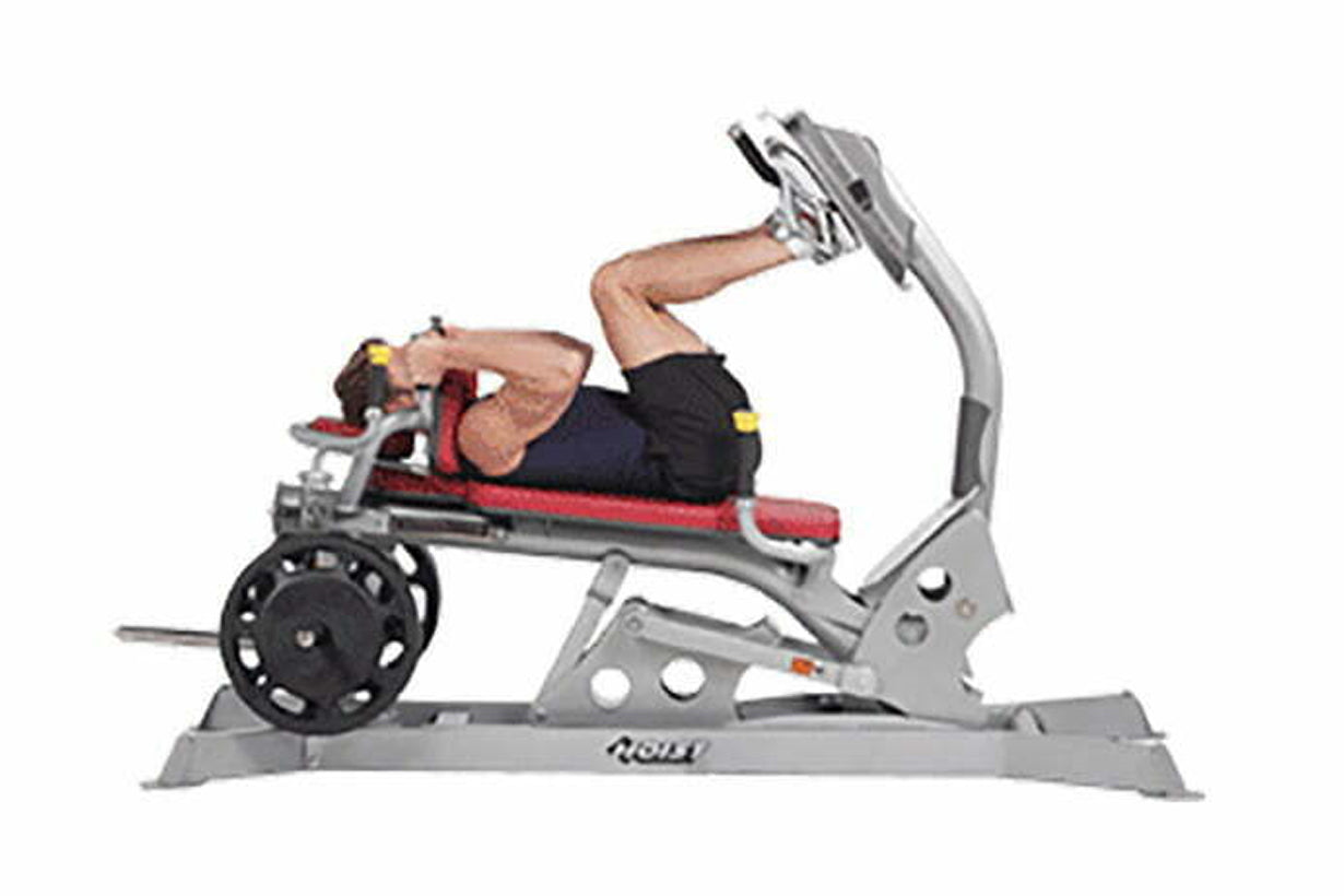Person using gray and red Hoist Dual Action Leg Press machine with black weight plate, demonstrating seated leg exercise posi