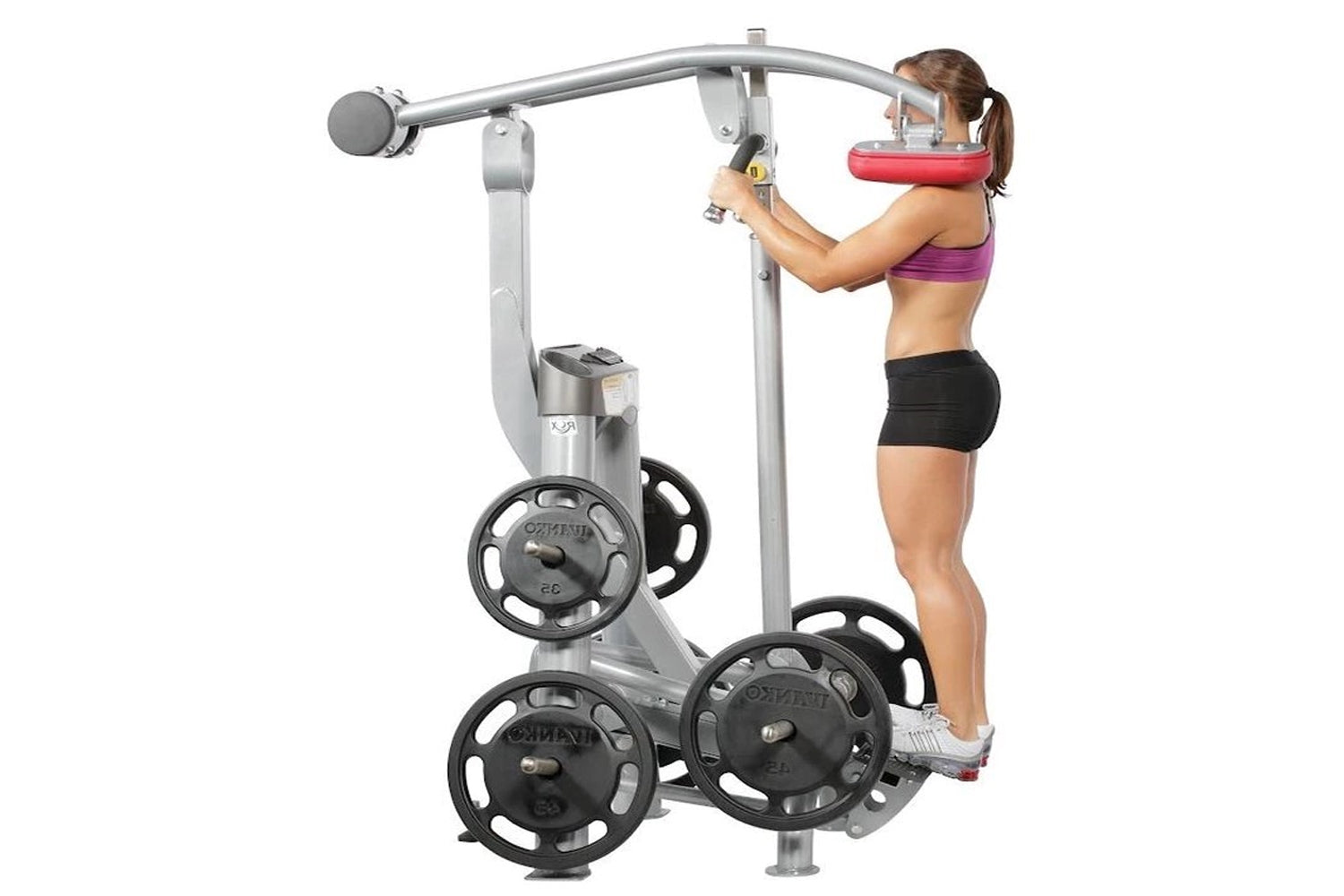 Woman using silver and black standing calf raise exercise machine with weight plates, wearing purple sports bra and black sho