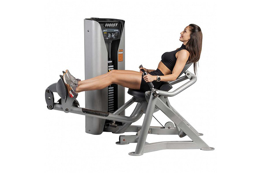 Hoist ROC-IT Lower Back Machine with woman demonstrating leg extension exercise, silver and black frame on white background