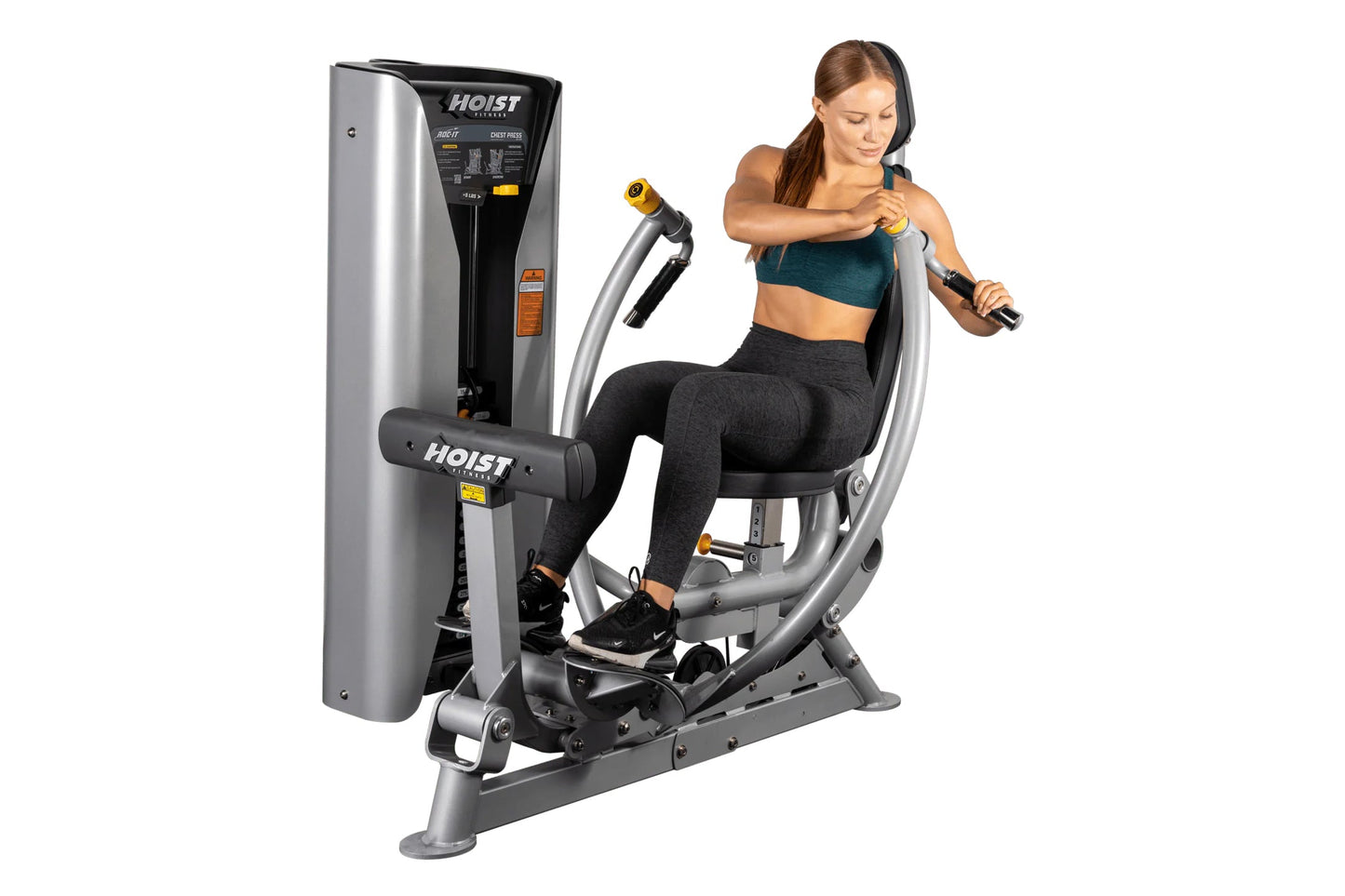 Hoist ROC-IT chest press machine with silver and black frame, woman in teal sports bra and black leggings demonstrating exerc