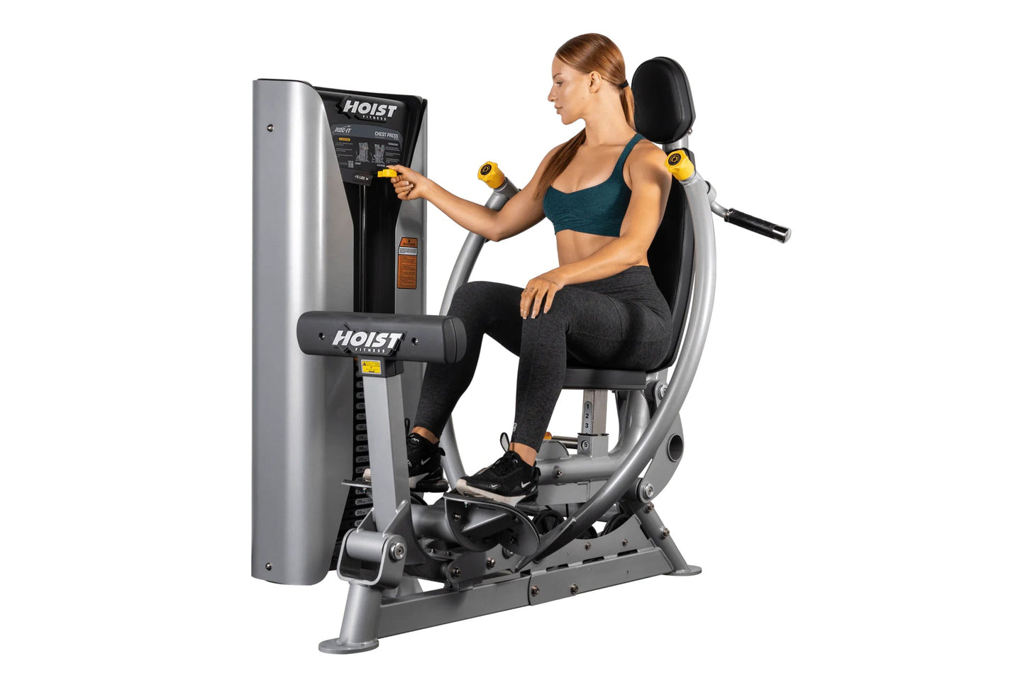 Hoist ROC-IT chest press machine with silver and black frame, woman in teal sports bra and black leggings demonstrating seate