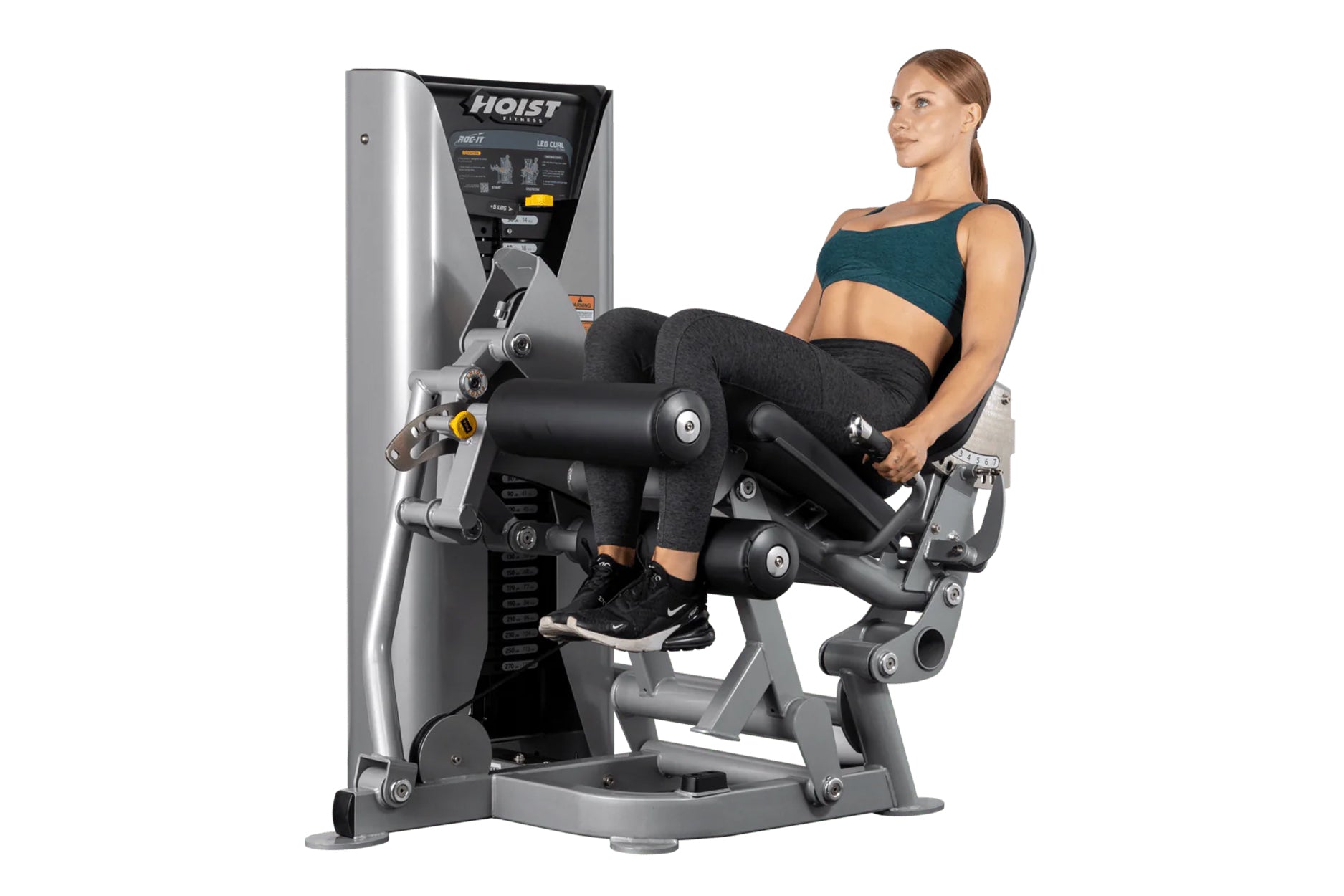 Woman using silver and black Hoist ROC-IT leg curl machine with digital display and padded leg extension attachment