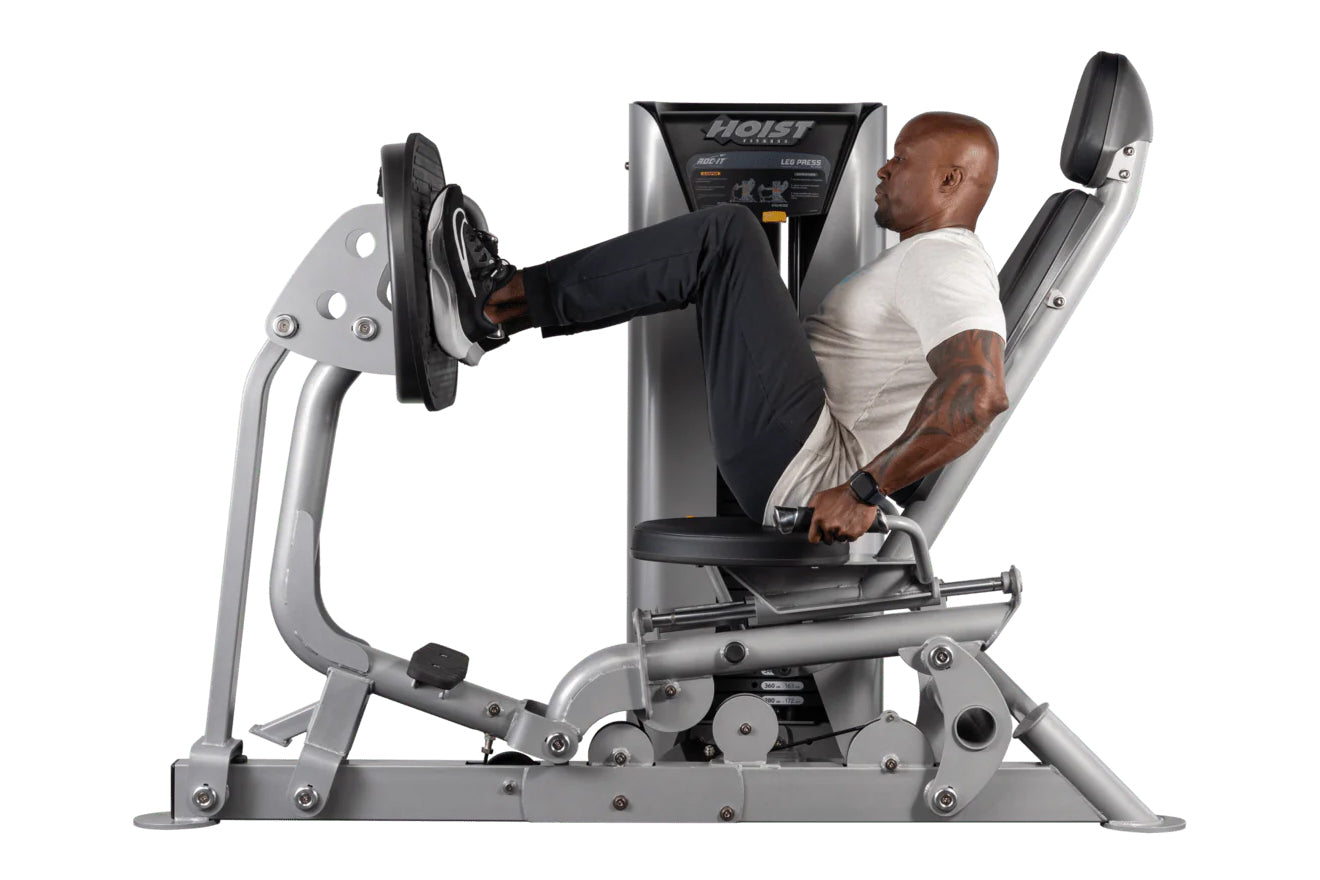 Hoist ROC-IT leg press machine with silver frame and black seat, shown in use by male model performing leg press exercise
