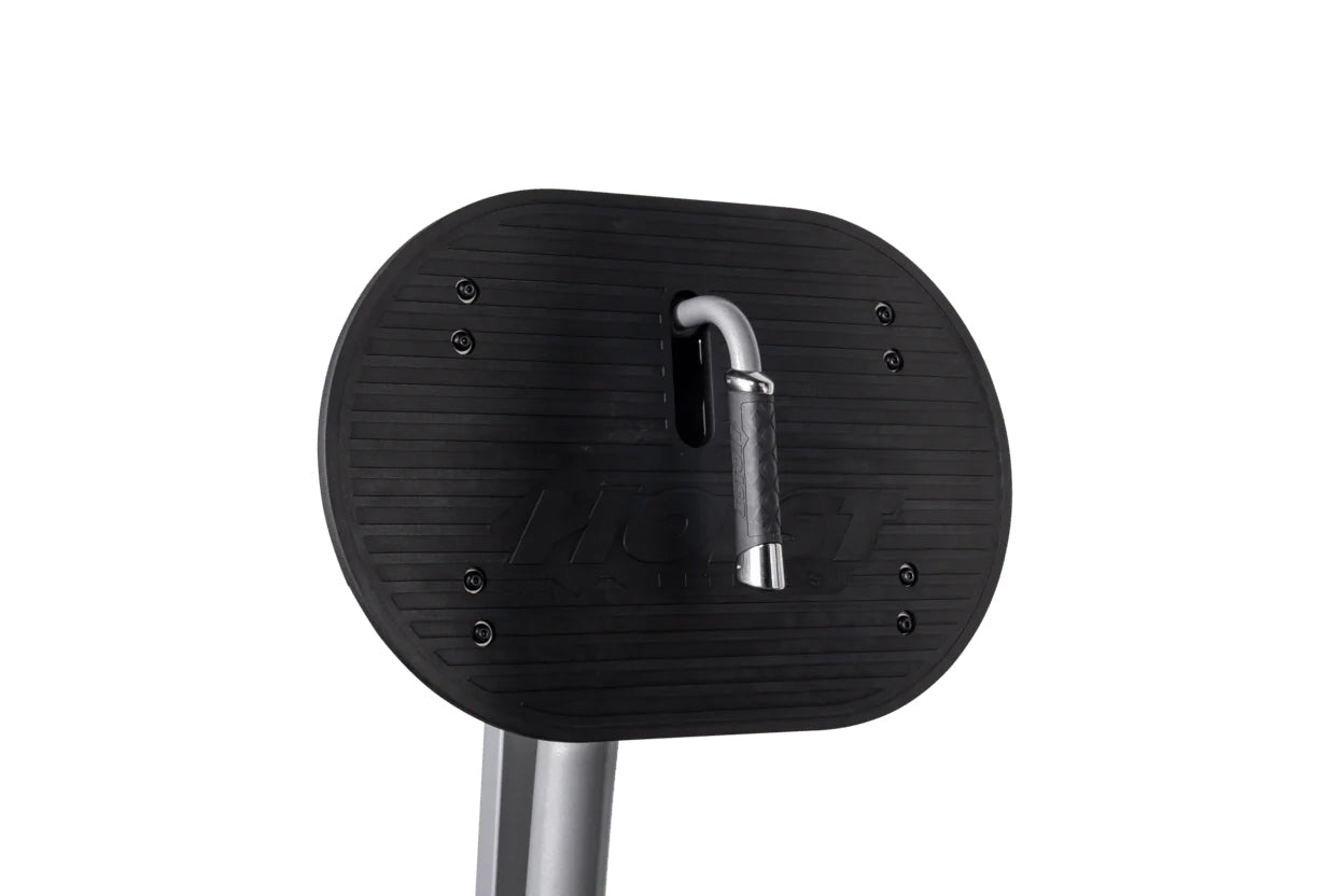 Black rubber foot plate with horizontal ridges attached to silver metal post, ROC-IT leg press machine component on white bac