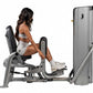 Woman seated on gray Hoist ROC-IT leg press machine with padded backrest and foot platform, demonstrating proper form on whit