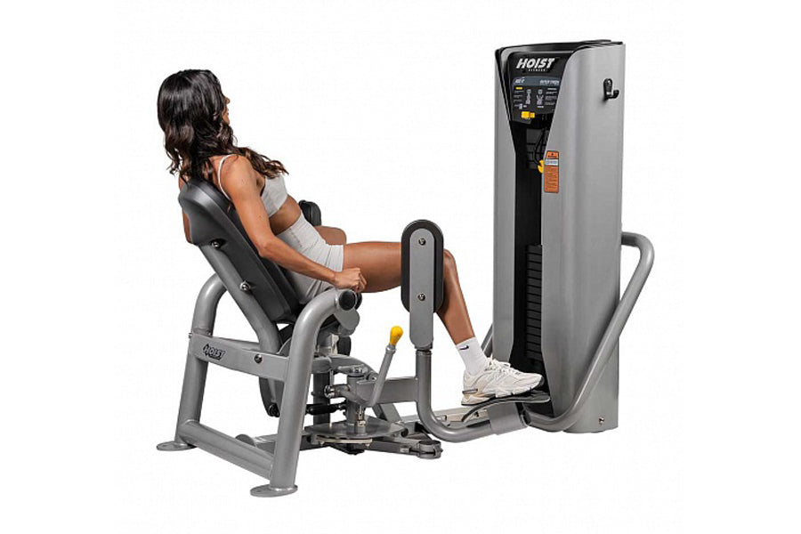 Woman using Hoist ROC-IT leg press machine with gray and black frame, digital control panel, and padded seat