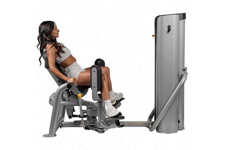 Woman using gray Hoist leg press machine with black accents, demonstrating proper form on equipment with extended leg platfor
