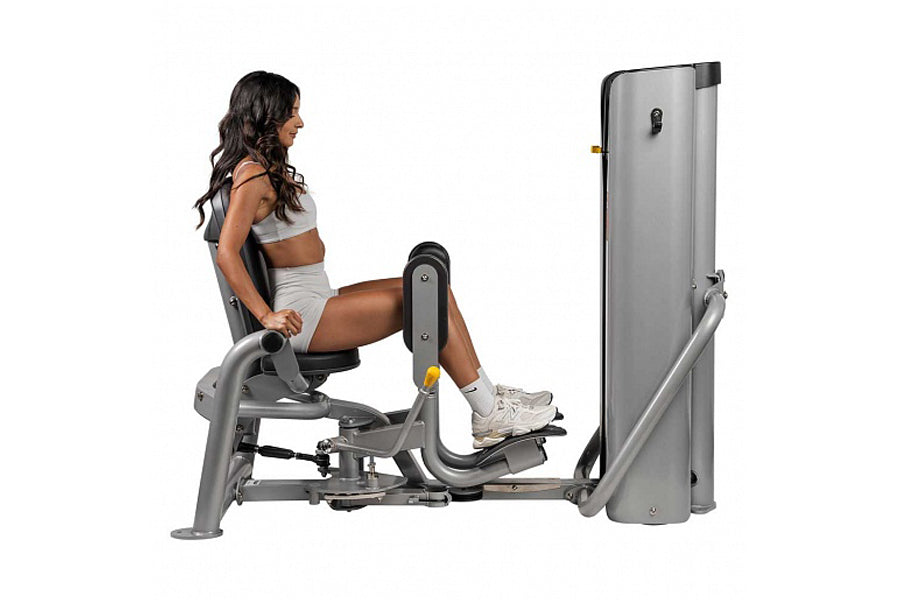 Woman using silver Hoist leg press machine with extended leg position on white background