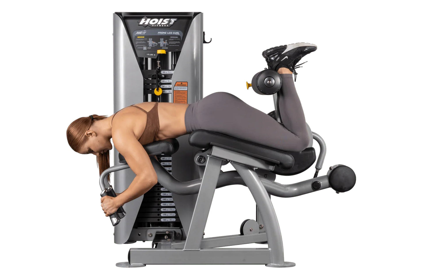 Hoist ROC-IT Prone Leg Curl Machine in silver and black with model demonstrating leg curl exercise position
