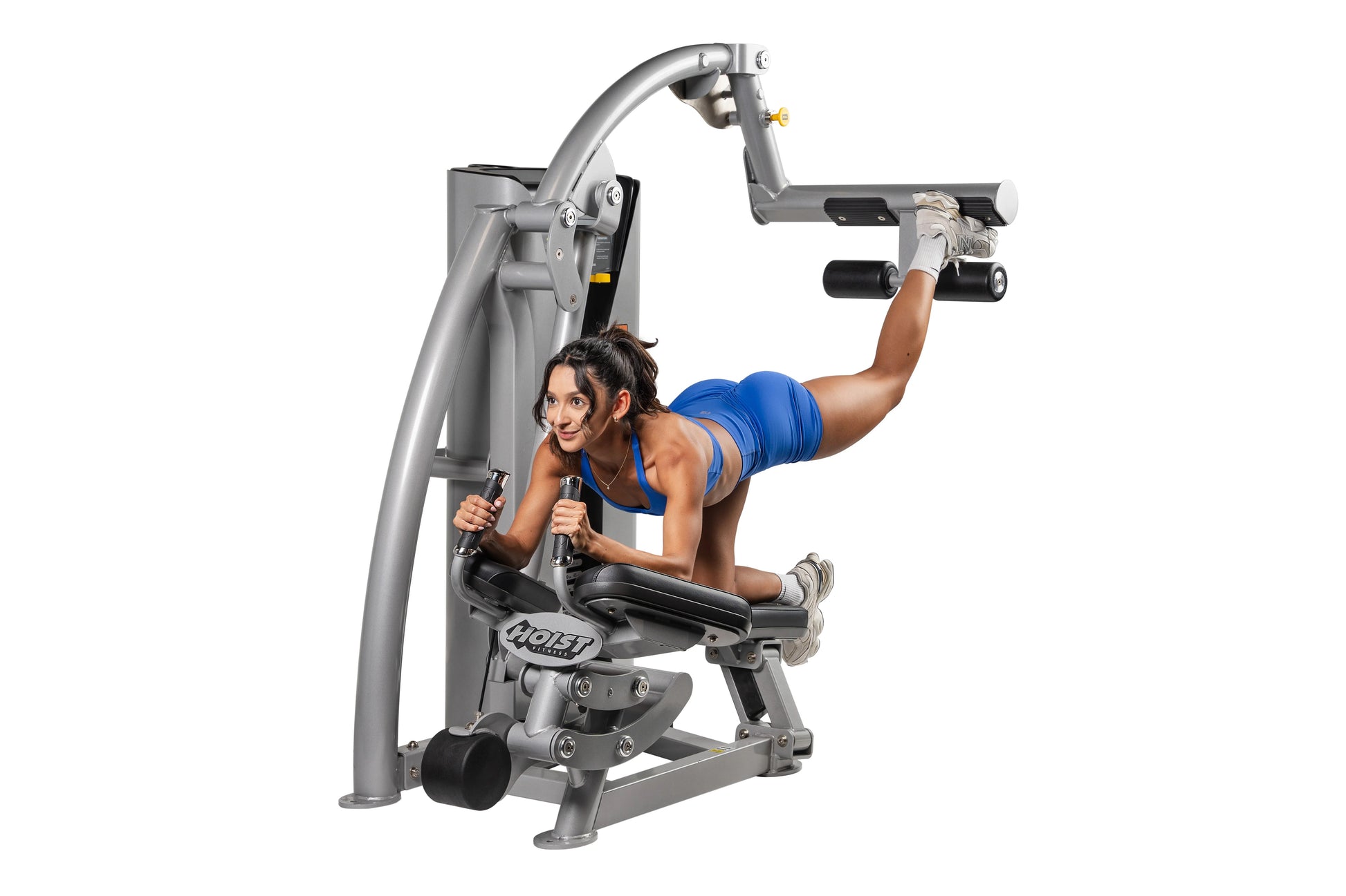Hoist ROC-IT Glute Master Machine, silver-gray frame with black handles and footrests, woman in blue sports bra demonstrating