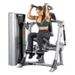 Woman using Hoist ROC-IT abs machine with silver frame and black padding, holding dumbbells overhead on white background