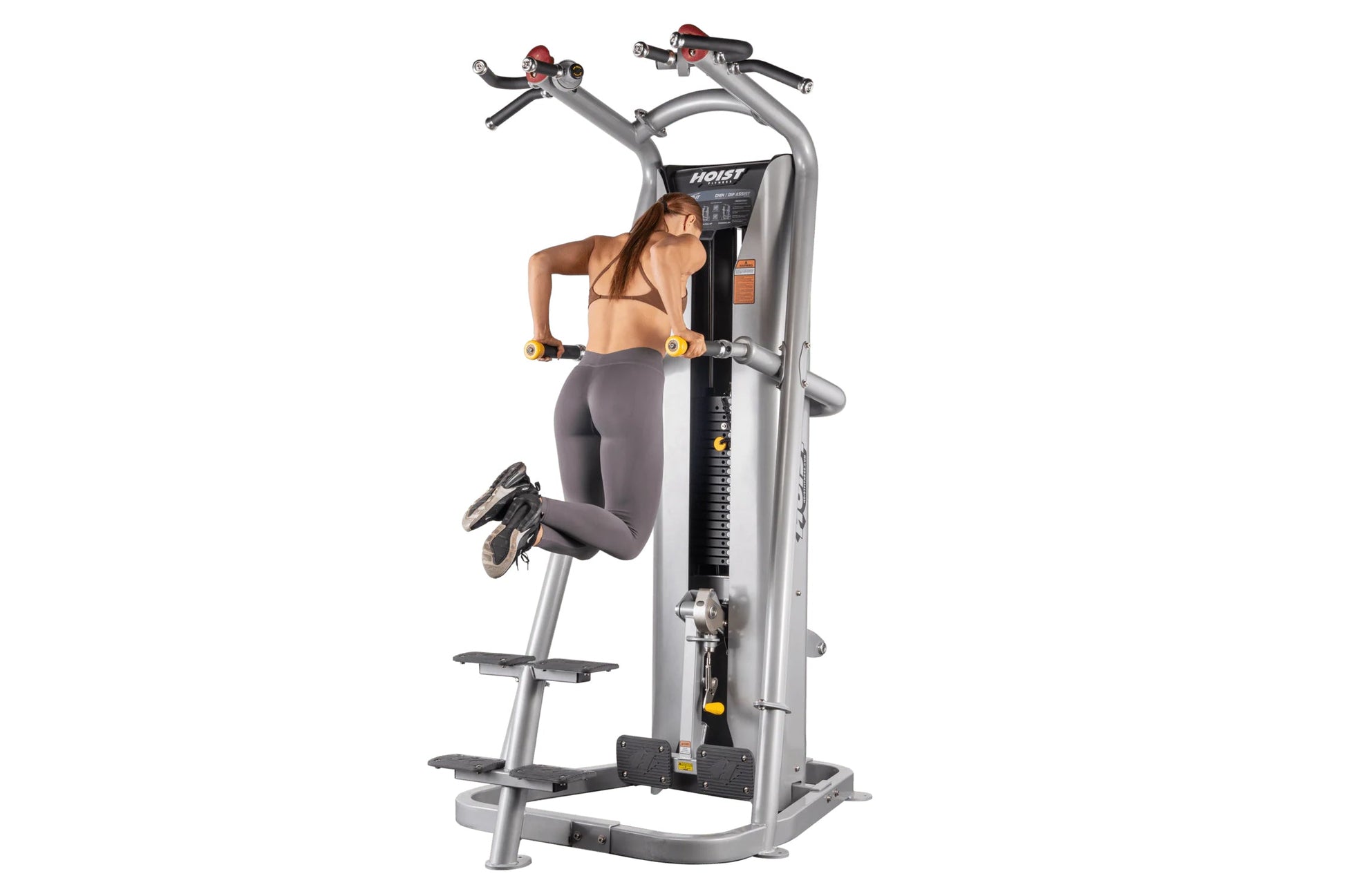 Silver and black Hoist ROC-IT chin/dip assist machine with dual handles, yellow accents, and footplate, demonstrated by model