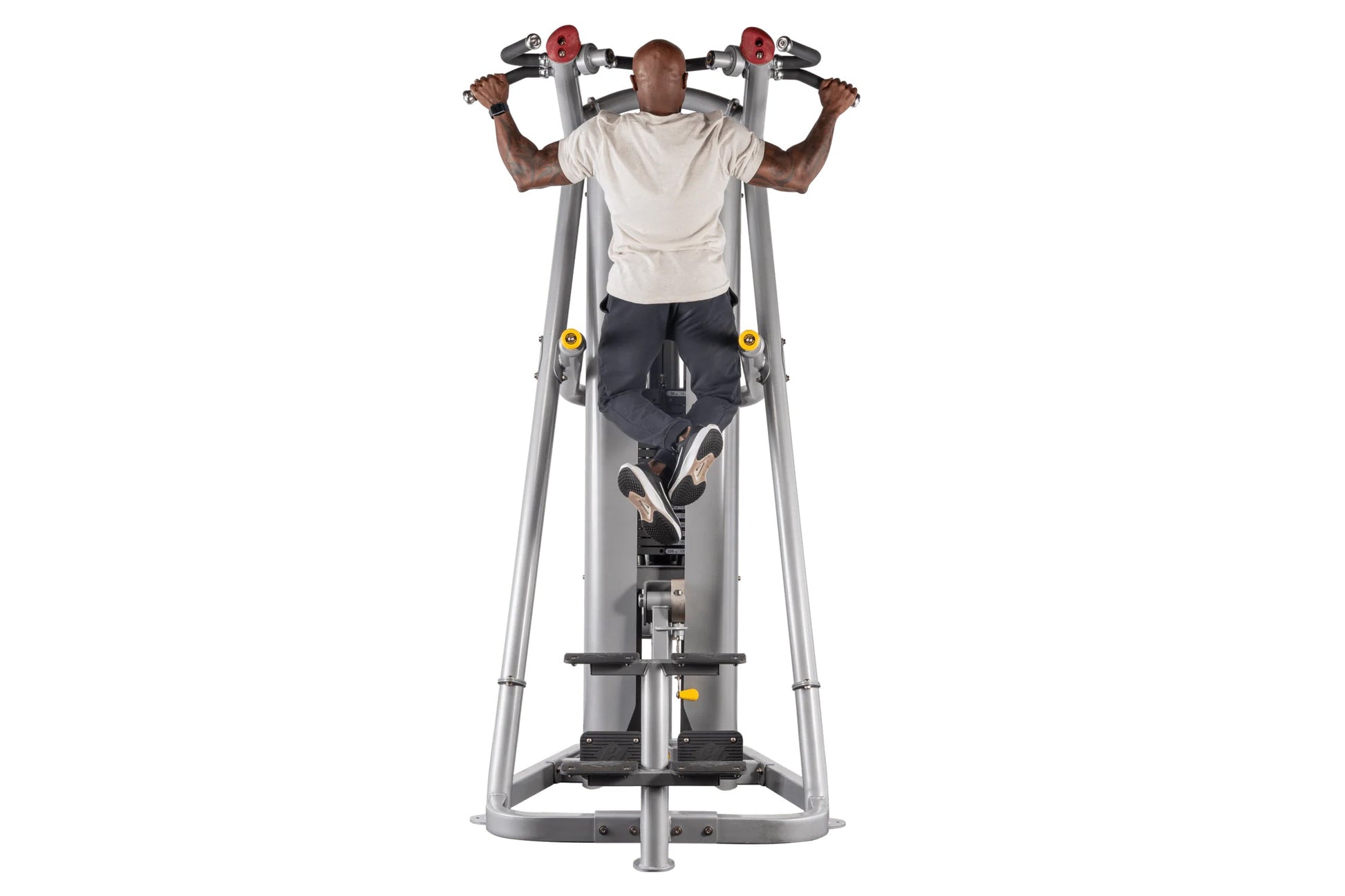 Man using silver and black chin dip assist machine with red and yellow handles, wearing white t-shirt and dark pants