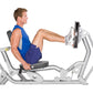 Man demonstrating leg press exercise on silver Hoist leg press machine with blue tank top, worn by model on white background