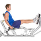 Man in blue tank top and navy shorts using silver Hoist leg press machine with extended leg position on white background