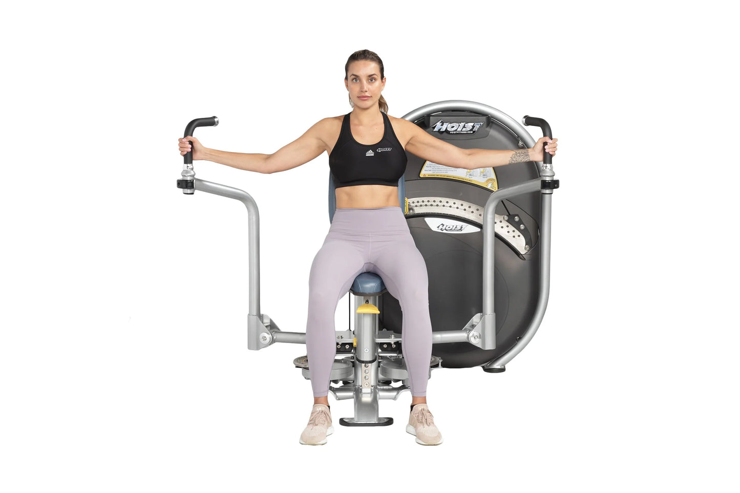 Woman using black and silver Hoist pec fly machine with handles extended, wearing black sports bra and lavender leggings on w