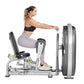 Woman using silver and black leg press machine with padded seat, worn by model in black sports bra and lavender leggings on w