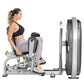 Woman using Hoist Club Line Inner/Outer Thigh exercise machine with gray and silver frame, black seat, and weight stack on wh