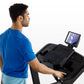 Man in blue t-shirt using black Horizon 5.0 AT treadmill with tablet display, side view on white background