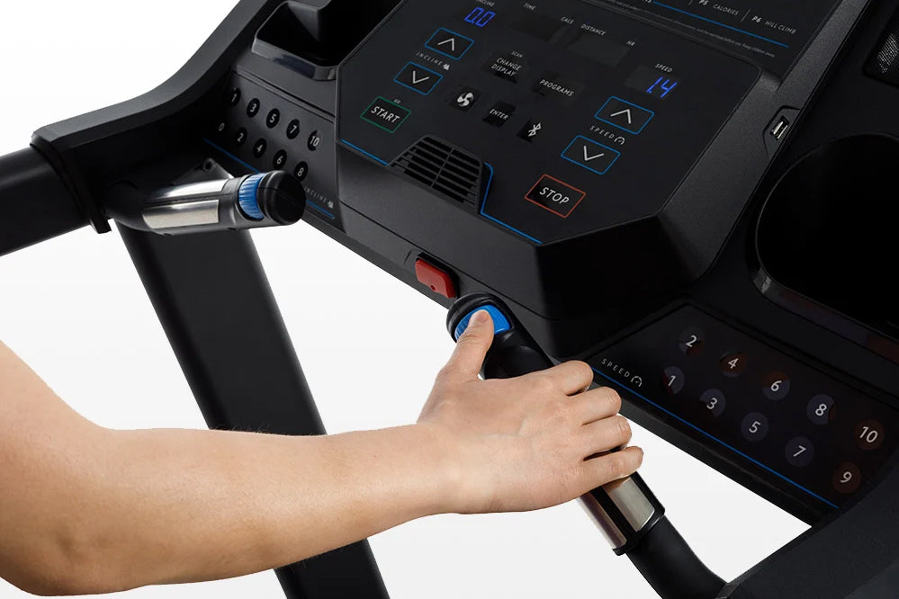 Hand on blue start button of black Horizon 5.0 AT treadmill with digital console display, worn by user