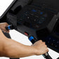 Person in blue shirt operating black treadmill console with blue-lit digital display and dual handlebar controls