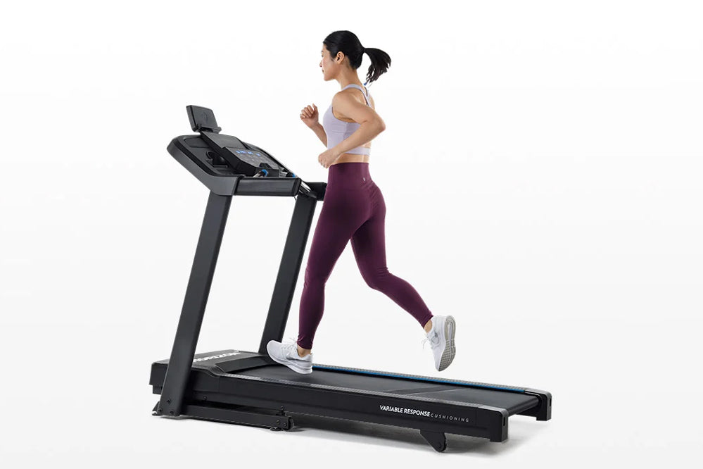 Woman running on black Horizon 5.0 AT treadmill wearing lavender sports bra and burgundy leggings, white sneakers