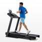 Man jogging on black Horizon 5.0 AT treadmill with blue touchscreen display, wearing blue t-shirt and light blue shorts