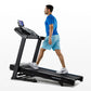 Man wearing blue t-shirt and light blue shorts running on black Horizon 5.0 AT treadmill with digital display on white backgr
