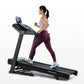 Woman running on black Horizon 5.0 AT treadmill with digital display, wearing lavender sports bra and burgundy leggings