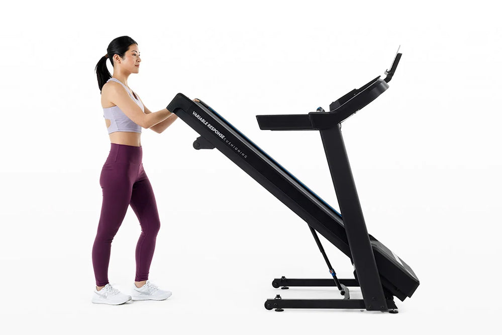 Woman in purple leggings and lavender sports bra using black Horizon 5.0 AT treadmill on white background