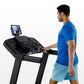 Man in blue t-shirt using black Horizon 5.0 AT treadmill with display screen, shown from side view on white background