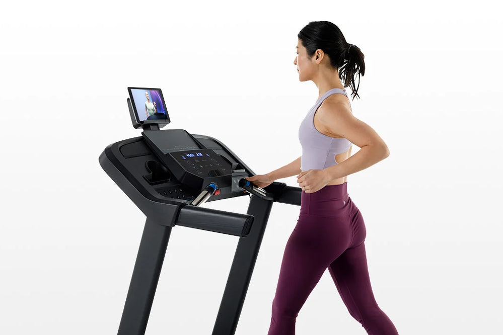 Woman in lavender tank top and burgundy leggings running on black Horizon 5.0 AT treadmill with digital display