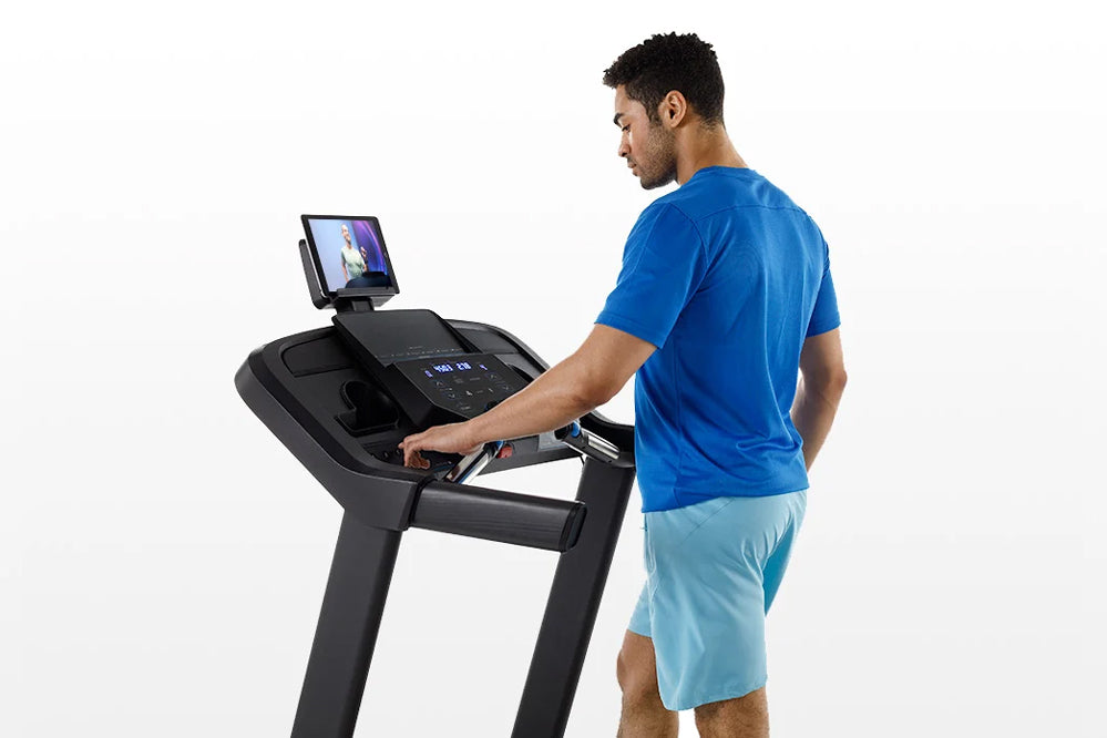 Man in blue shirt using black Horizon 5.0 AT treadmill with attached tablet display, shown in profile view