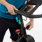 Man in blue shirt and black shorts on stationary bike with black handlebars and digital console, showing seat height adjustme