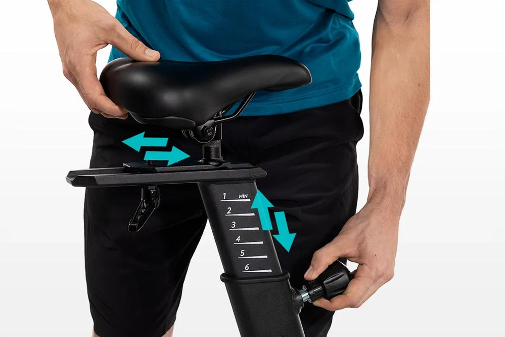 Black stationary bike seat with adjustment arrows and numbered seatpost showing multiple height positions, worn by model in t