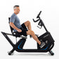 Man using black Horizon 5.0 R recumbent exercise bike with blue accent trim on white background