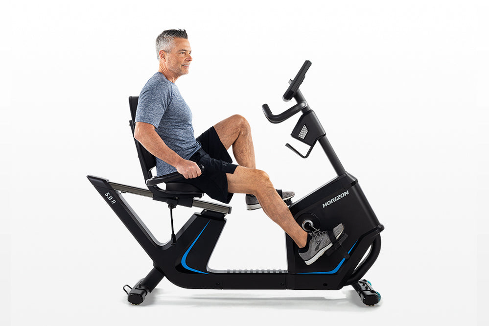 Man using black Horizon 5.0 R recumbent exercise bike with blue accent trim on white background