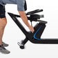 Man using black recumbent exercise bike with blue accent details and adjustable seat, worn with navy shorts and gray sneakers