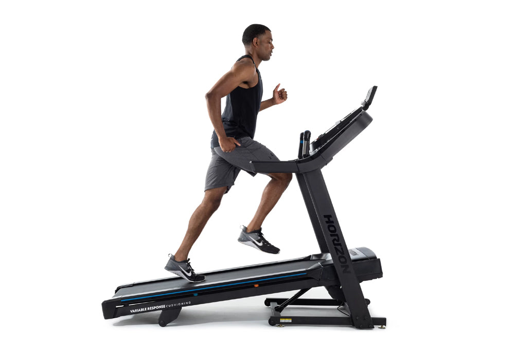 Man running on black Horizon 7.0 AT treadmill with blue accents, worn by model on white background