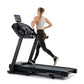 Woman running on black Horizon 7.0 AT treadmill with digital display, wearing white sports bra and black leggings
