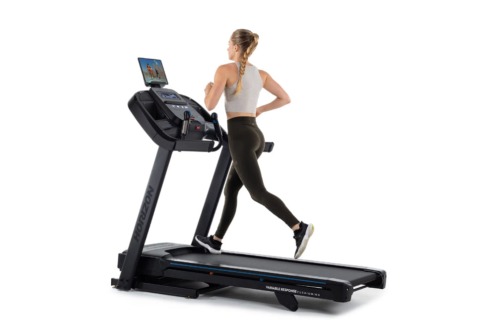 Woman running on black Horizon 7.0 AT treadmill with digital display, wearing white sports bra and black leggings