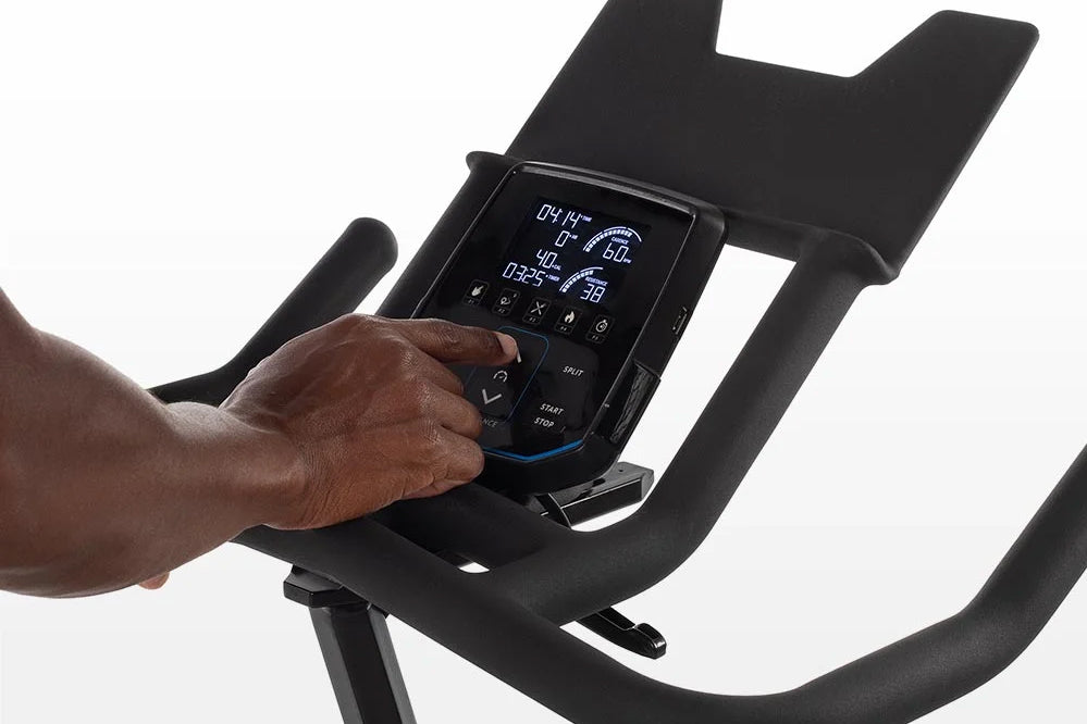 Horizon 7.0 IC indoor cycle console with digital display showing workout metrics, operated by hand on white background