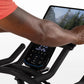 Person wearing coral tank top on Horizon 7.0 IC stationary bike with digital console display and tablet holder showing mounta