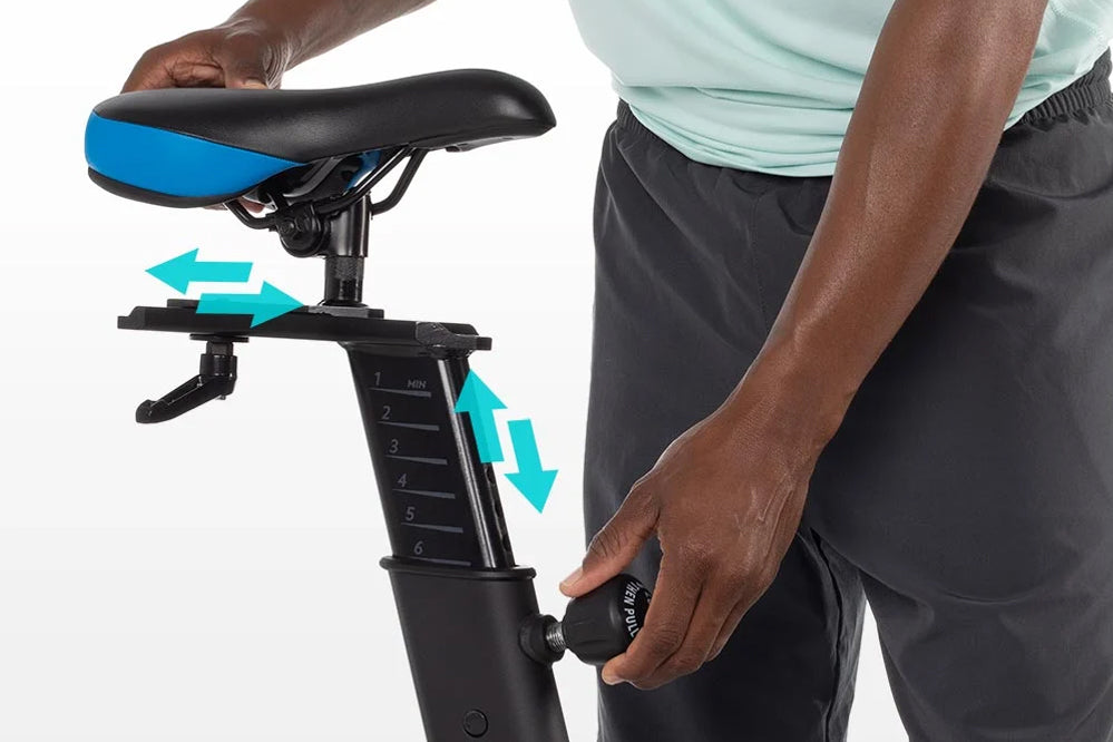 Black and blue stationary exercise bike seat with adjustable height and resistance dial, shown with model demonstrating adjus