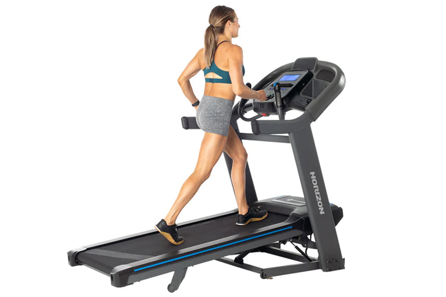 Woman in teal sports bra and gray shorts running on black Horizon treadmill with blue accents and digital display