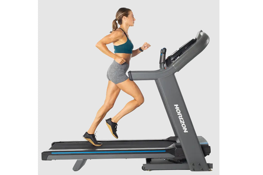 Woman running on Horizon treadmill with gray frame, black running deck, and blue accent stripe, treadmill shown in profile vi