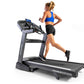 Woman running on Horizon 7.8 AT treadmill wearing blue sports bra and black shorts, white sneakers, on white background