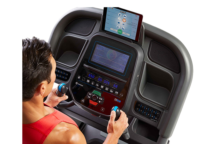 Man in red shirt using Horizon treadmill with dual digital display screens and control console